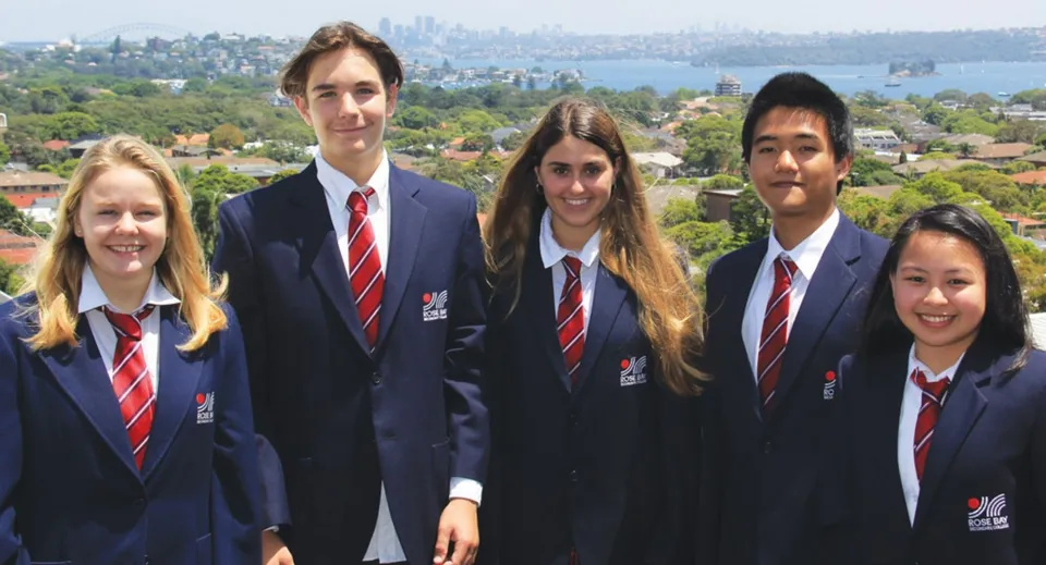 Un gruppo di studenti della Rose Bay High School è insieme con un paesaggio urbano sullo sfondo.