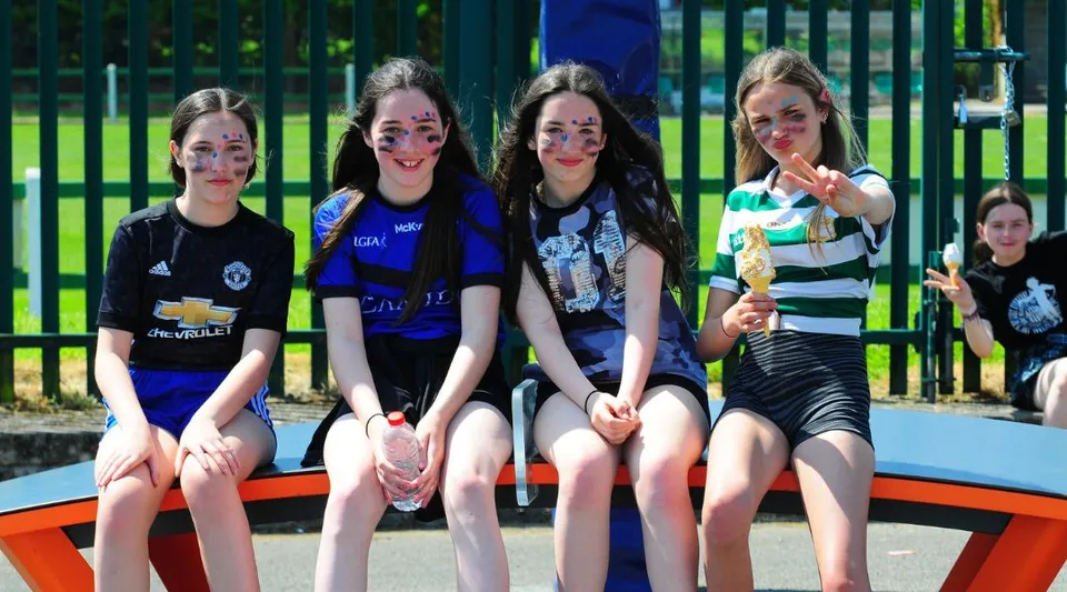 Un gruppo di studentesse siede insieme in un parco giochi colorato nel terreno della St Ailbe's School.
