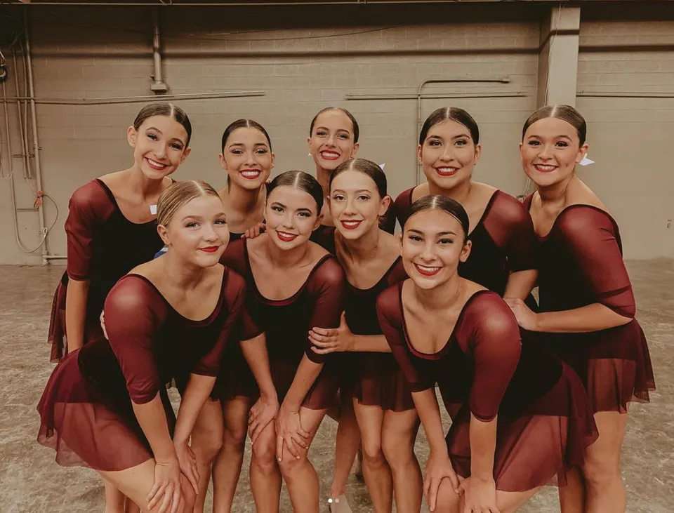 Un gruppo di studentesse della Campo Verde High School posa su un palco con abiti rossi e neri.