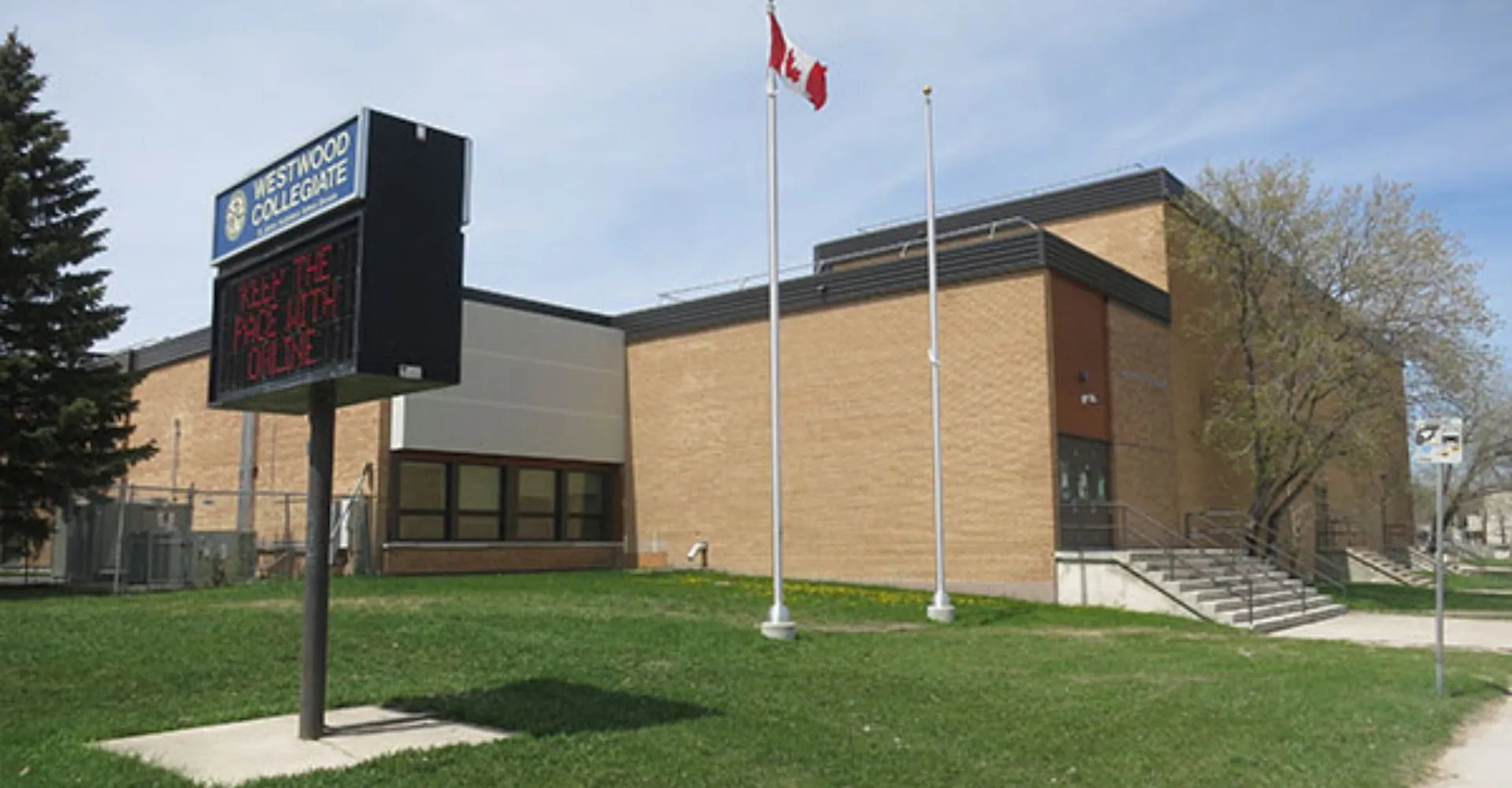 L'edificio moderno a più piani con la bandiera canadese fa parte della Westwood Collegiate ed è circondato da prati e alberi.