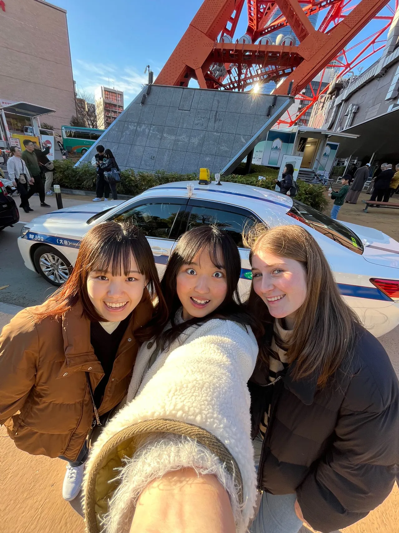 Tre ragazze sorridenti si scattano un selfie davanti alla Torre di Tokyo