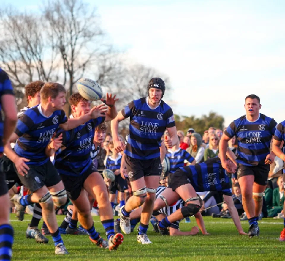Un gruppo di giocatori di rugby in maglia blu durante una partita sul campo della Christchurch Boys High School.
