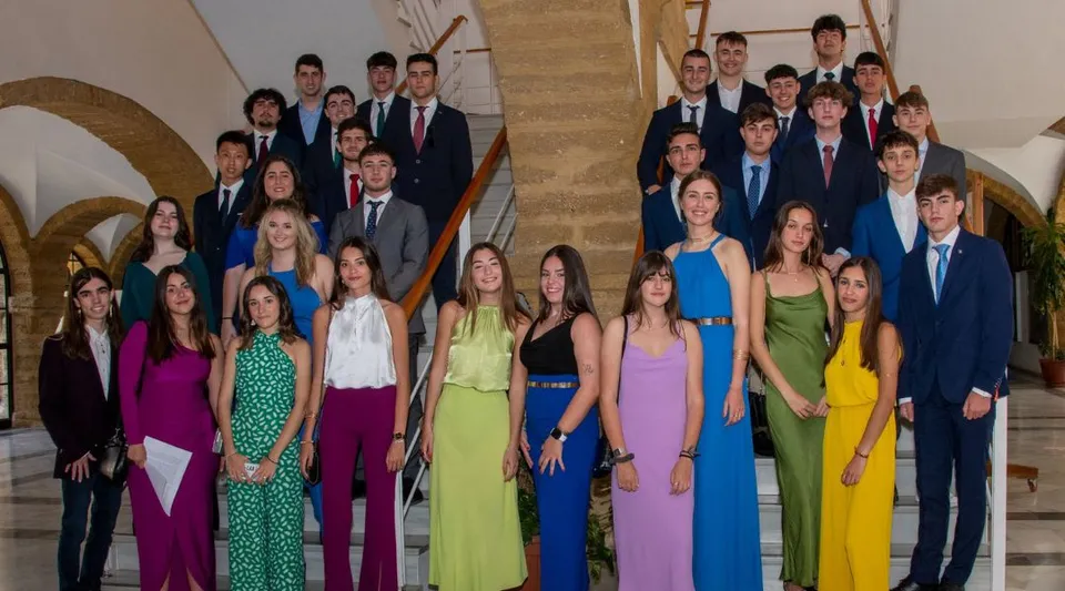 Un gruppo di studenti e studentesse in abito formale si trova insieme in un contesto architettonico decorato nel campus del Colegio Argantonio.