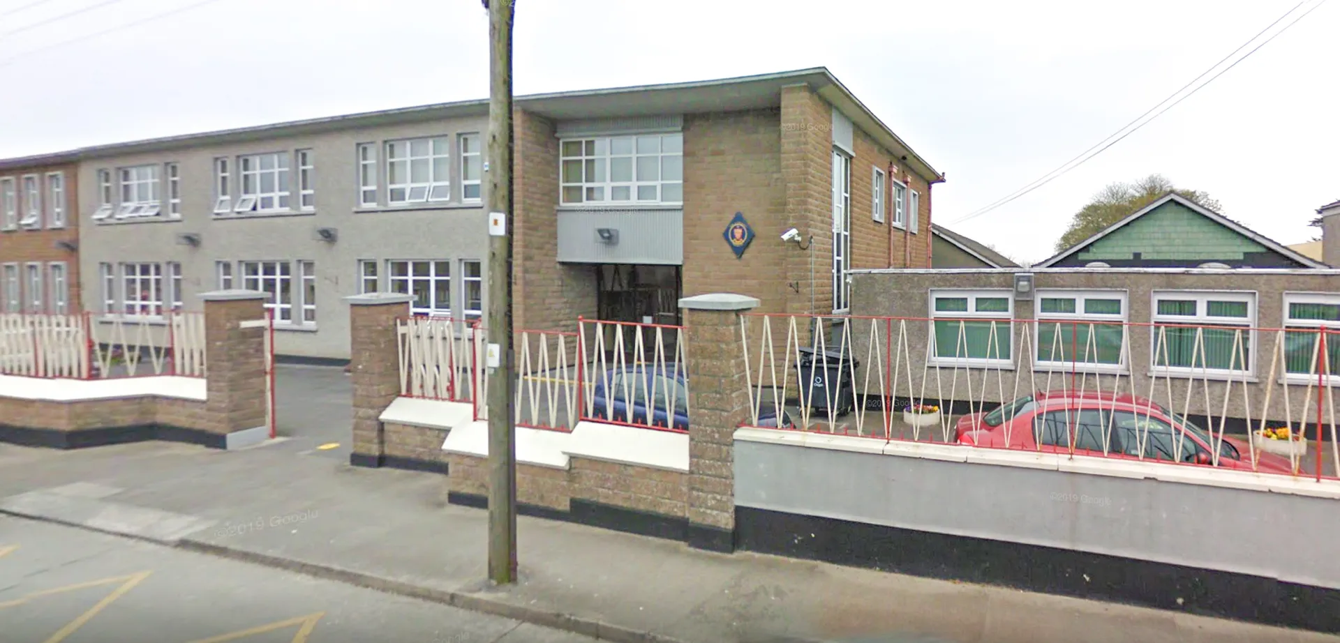 L'edificio a più piani in mattoni della Sacred Heart Secondary School a Drogheda con grandi finestre e un'area recintata in primo piano.