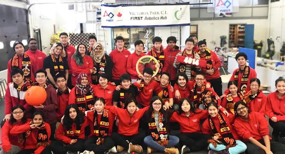 Un grande gruppo di studenti del Victoria Park Collegiate Institute posa in giacche sportive rosse in una palestra.