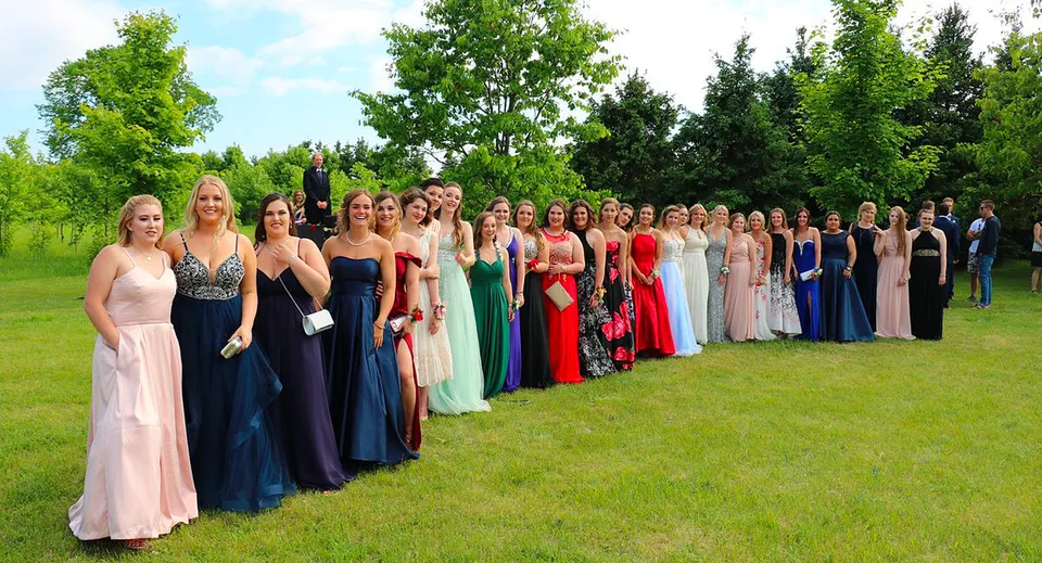 Un gruppo di giovani donne in abiti eleganti si trova su un prato nel campus della Elmvale District High School.