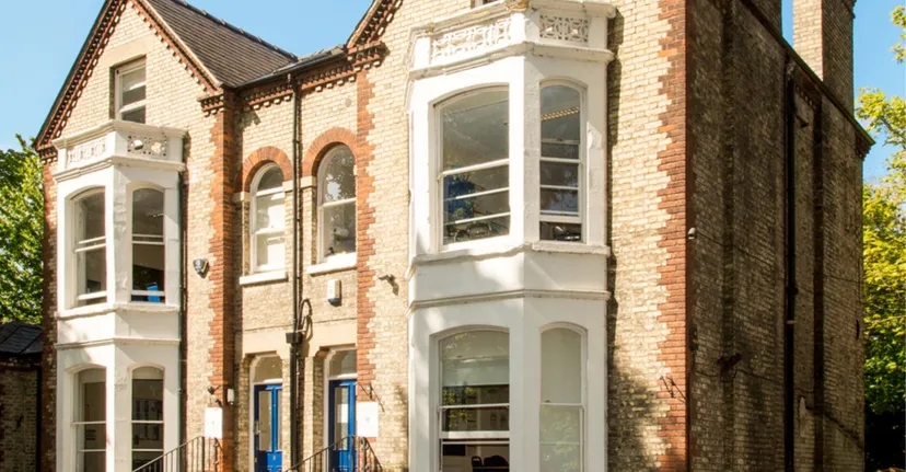 L'edificio in mattoni a più piani con finestre decorate si trova nel campus del St. Andrew’s College a Cambridge.