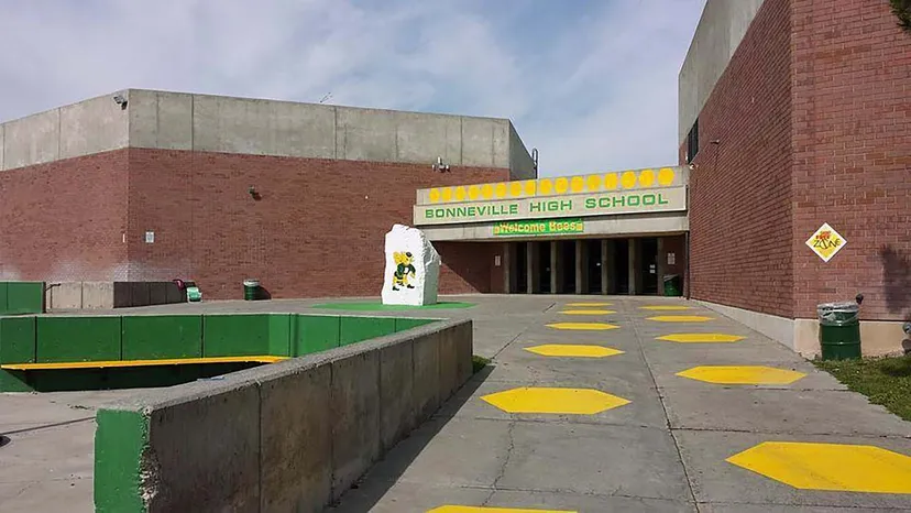 Si vede l'edificio della Bonneville High School con un percorso giallo e verde verso l'ingresso e un piazzale pavimentato.