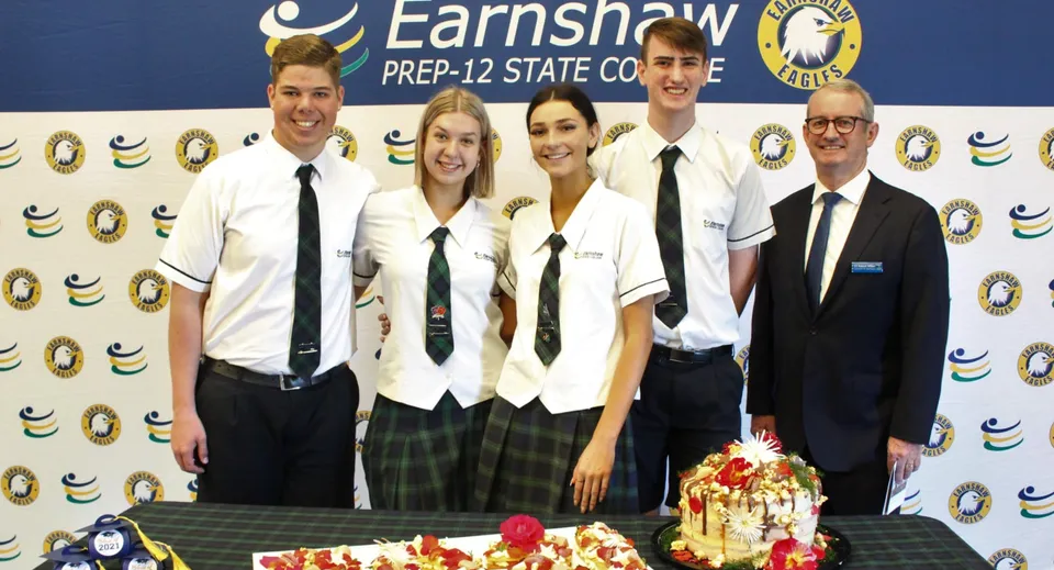 Un gruppo di studenti posa davanti a uno sfondo con il logo dell'Earnshaw State College.