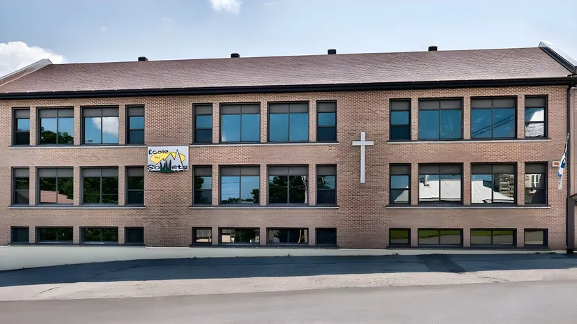 L'edificio in mattoni a più piani della École des Sept Sommets si trova in un'area urbana con un piazzale lastricato.