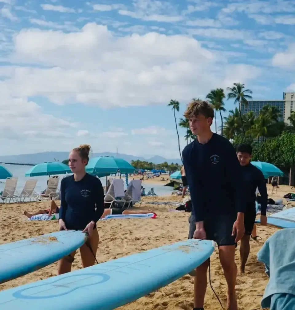 Zwei Jugendliche stehen mit Surfbrettern am Strand