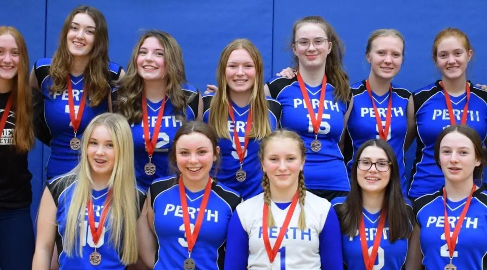 Un gruppo di studentesse del Perth & District Collegiate Institute indossa divise blu e mostra le proprie medaglie su uno sfondo blu.