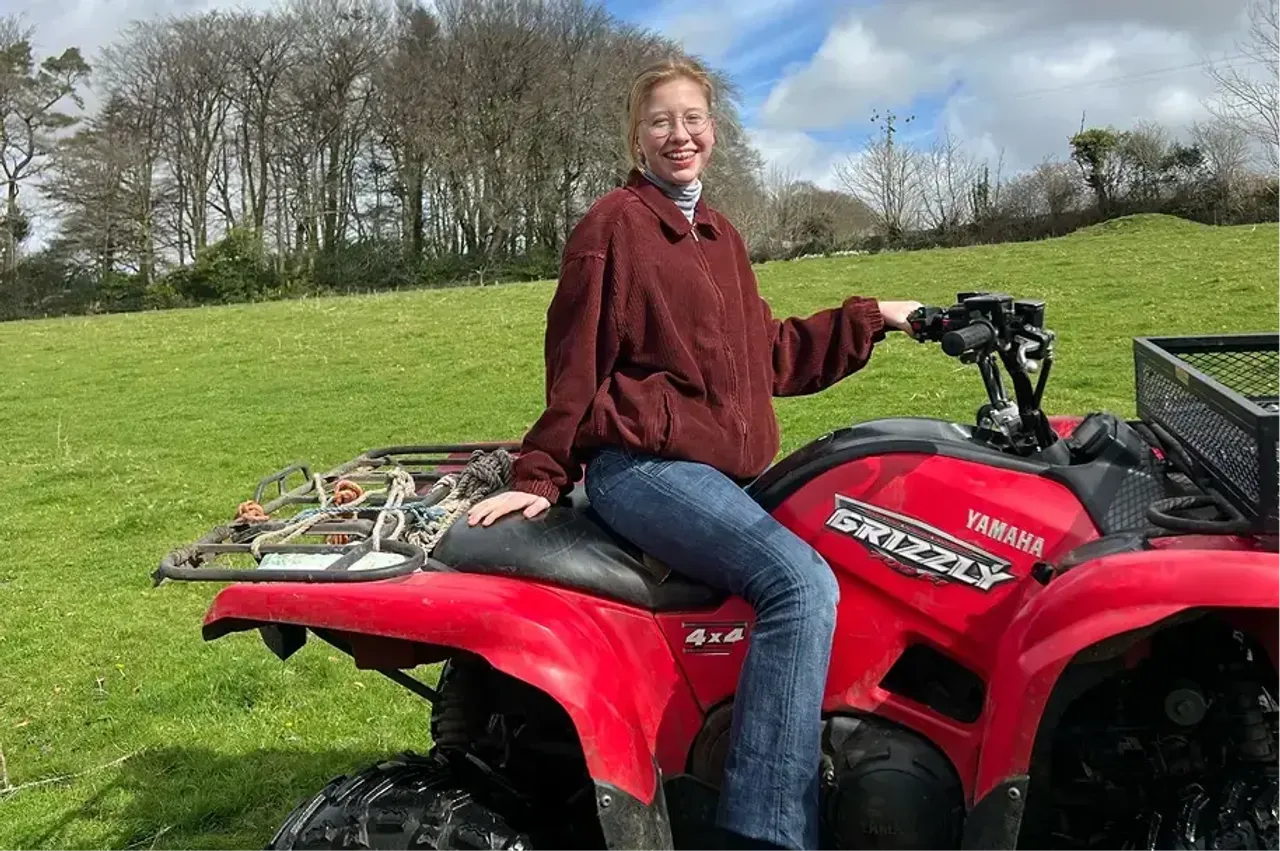 Ragazza sorridente seduta su un quad Yamaha rosso in un prato verde