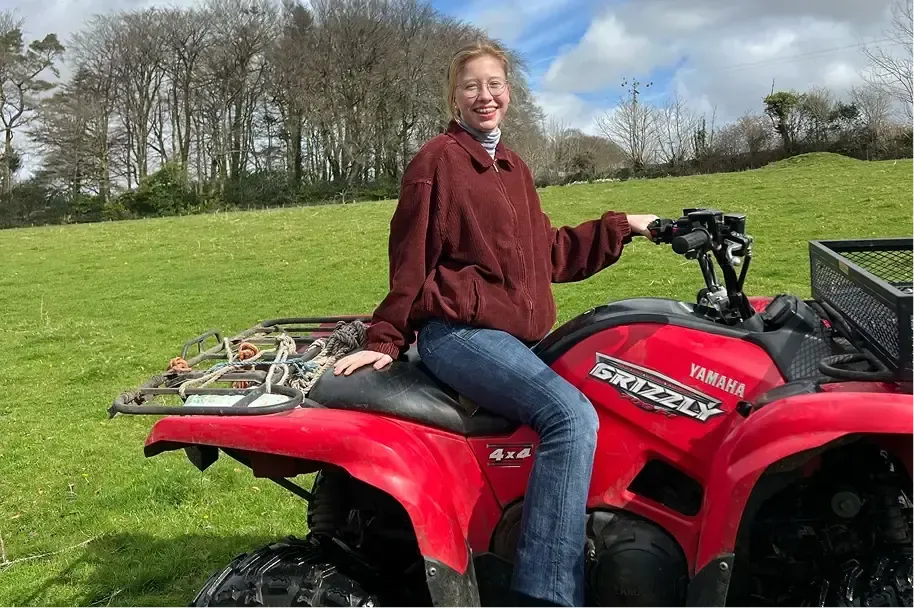 Ragazza sorridente seduta su un quad Yamaha rosso in un prato verde