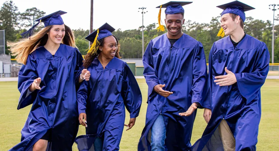 Quattro diplomati dell'Onslow College in piedi insieme su un prato davanti agli alberi.