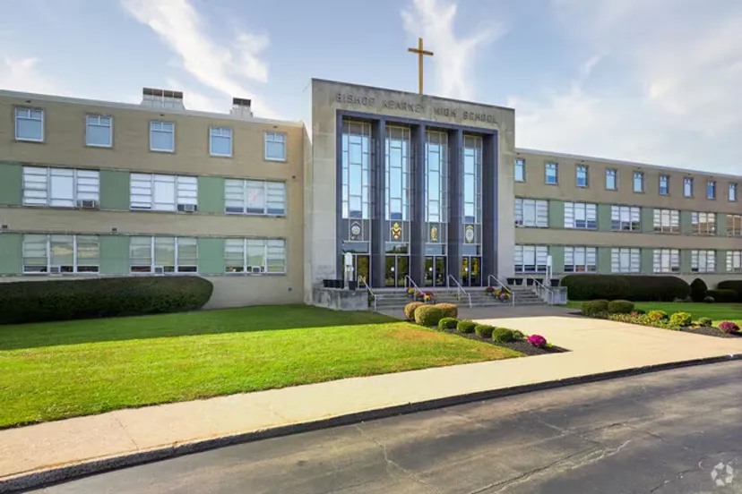 L'edificio moderno a più piani della Bishop Kearney High School, con una croce sulla facciata, è circondato da un prato ben curato.