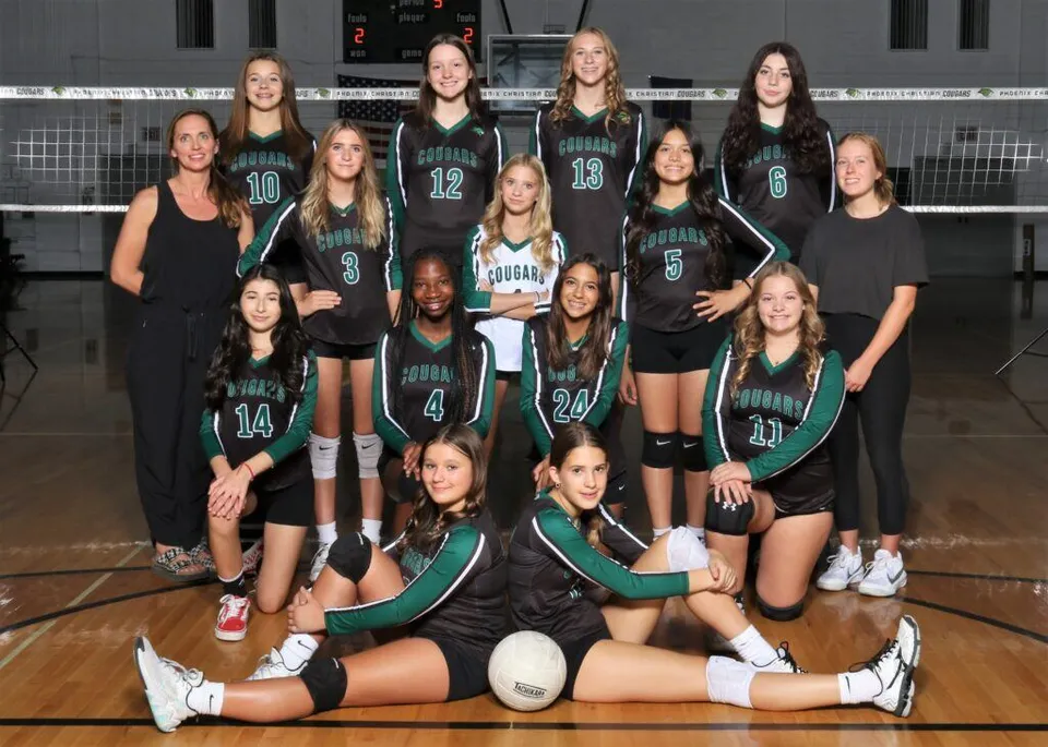 Un gruppo di giovani giocatrici di pallavolo in posa sul campo da pallavolo della Phoenix Christian Preparatory School.