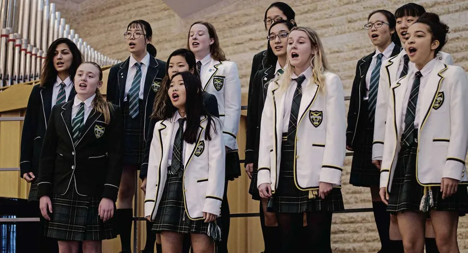 Studentesse della Balmoral Hall High School sono nell'aula magna e cantano insieme in coro.