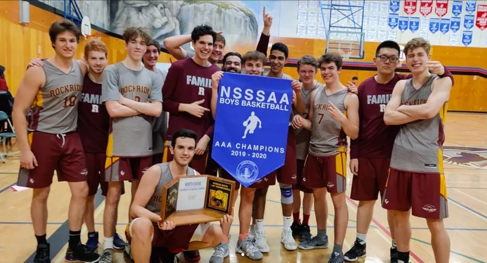 Un gruppo di giocatori di pallacanestro della Rockridge Secondary School tiene con orgoglio uno striscione del campionato nella palestra.