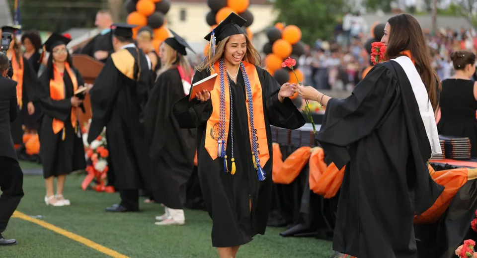 Un gruppo di diplomati in toga nera alla cerimonia di diploma della Bayridge Secondary School su un prato.
