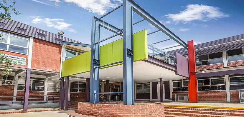 L'edificio moderno e multicolore della Mount Barker High School si vede con strutture in vetro e acciaio contro un cielo blu.