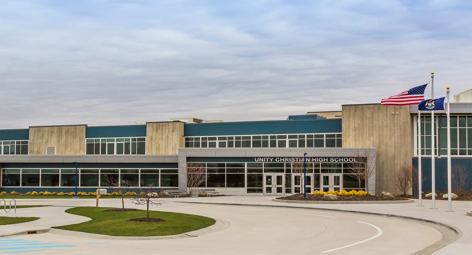 Si vede il moderno edificio scolastico della Unity Christian High School con la bandiera americana e vialetti curati.
