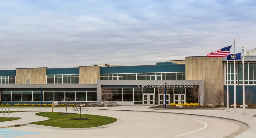 Si vede il moderno edificio scolastico della Unity Christian High School con la bandiera americana e vialetti curati.