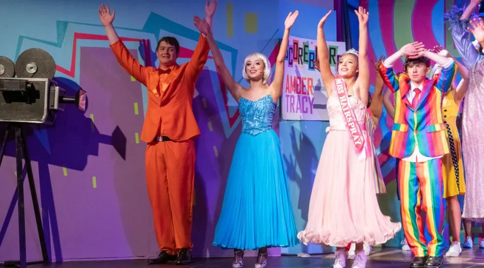 Un gruppo di studenti e studentesse del Portumna Community College si presenta in costumi colorati su un palco vivace.