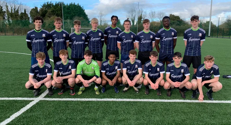 Un gruppo di giovani calciatrici e calciatori posa sul campo in erba sintetica del Moate Community College.