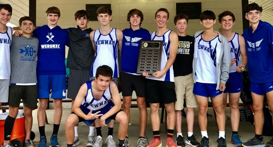 La squadra di pallacanestro della Newman Central Catholic High School posa insieme a un trofeo di vittoria.