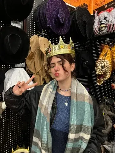 Chica con una corona de juguete posando en una tienda de disfraces de Halloween