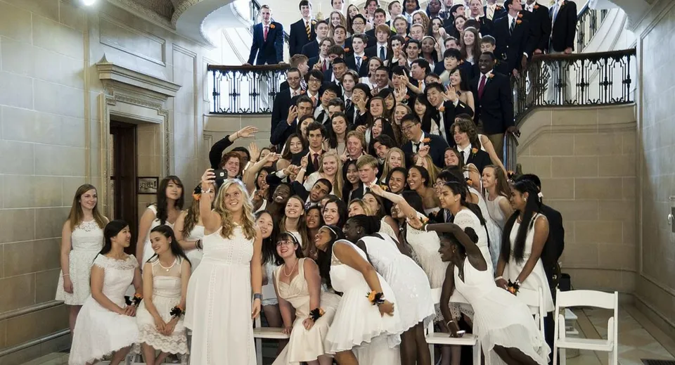 Un grande gruppo di persone in abito formale si riunisce nello storico salone d'ingresso della Lake Forest Academy.