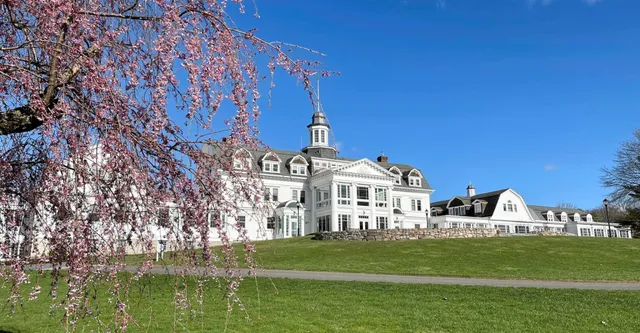 Il storico edificio principale della The Salisbury School si trova su un prato verde con ciliegi in fiore in primo piano.