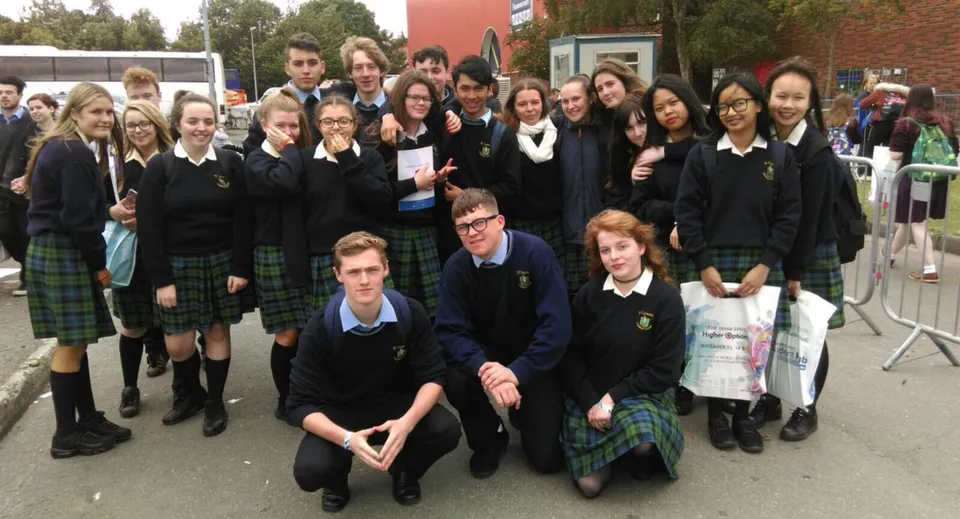 Un grande gruppo di studenti e studentesse del St. Tiernan’s College si trova insieme all'aperto davanti a un edificio scolastico.