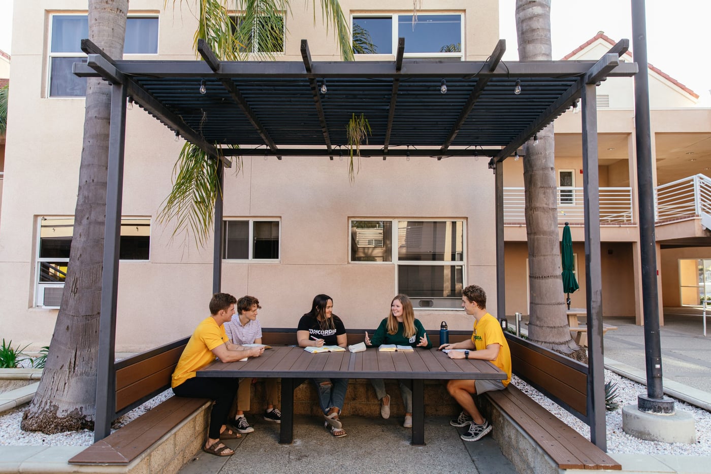 Studenti seduti insieme sotto una pergola nel cortile di una residenza a Los Angeles