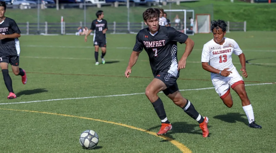 Due studenti della Pomfret School si contendono la palla su un campo di calcio con la porta sullo sfondo.