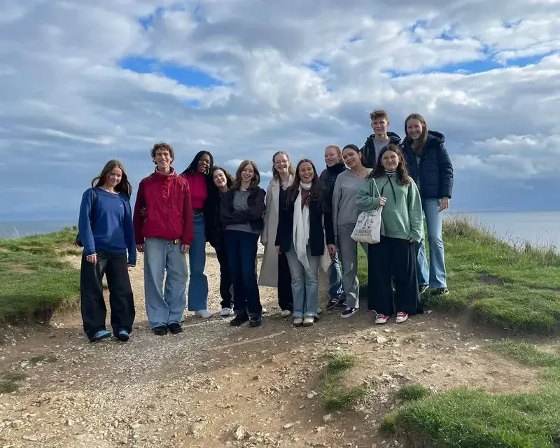 Grupo de alumnos posando en un acantilado con el mar al fondo