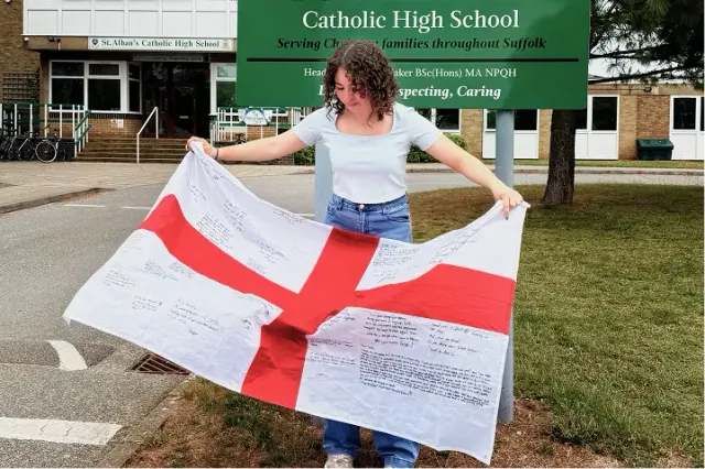 Una studentessa mostra una bandiera inglese firmata davanti all'ingresso di una scuola
