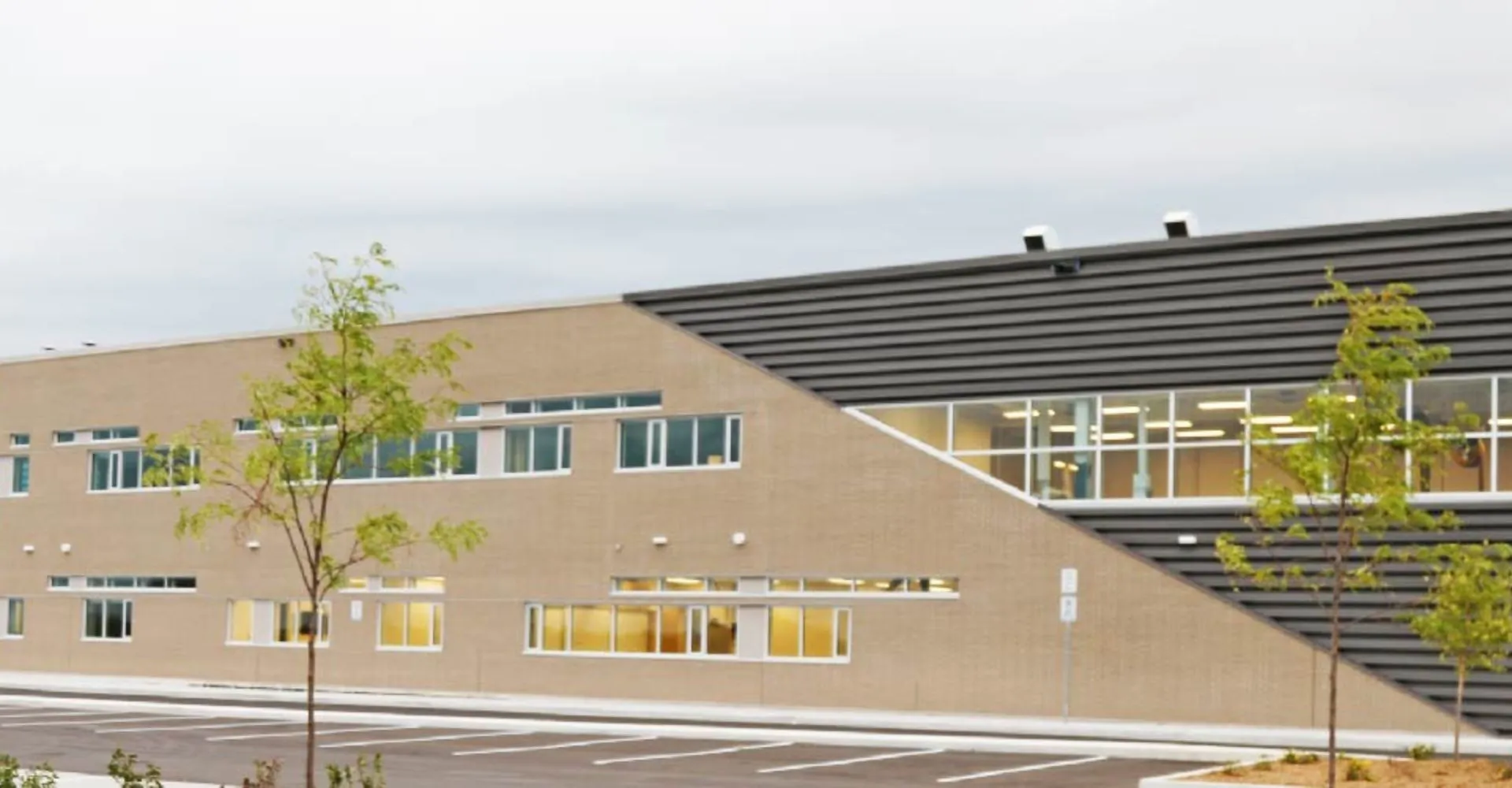 L'edificio moderno a più piani della Maple Ridge Secondary School in Ontario è circondato da alberi e da un parcheggio.
