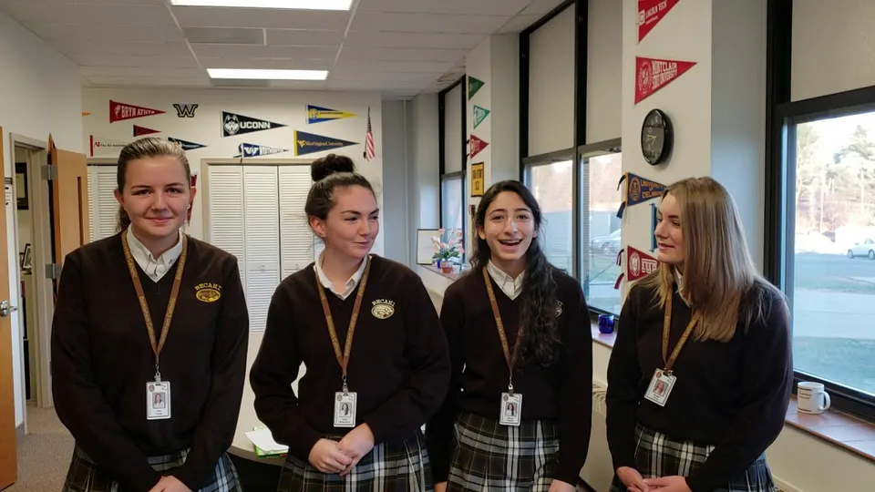 Quattro studentesse della Bethlehem Catholic School in divisa scolastica sono in piedi in un'aula.