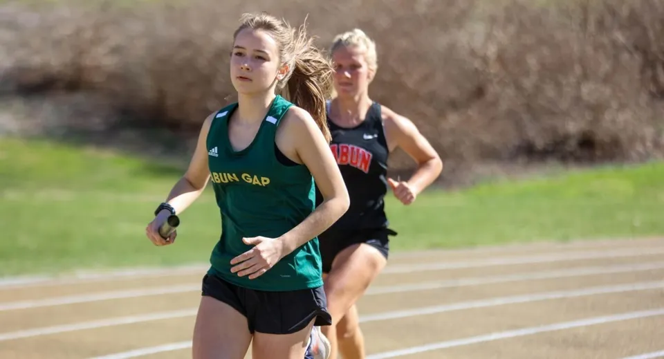 Un'atleta della Rabun Gap-Nacoochee School corre con un testimone sulla pista di atletica.