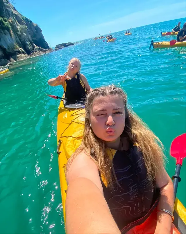 Due ragazze in kayak sul mare turchese lungo una costa rocciosa