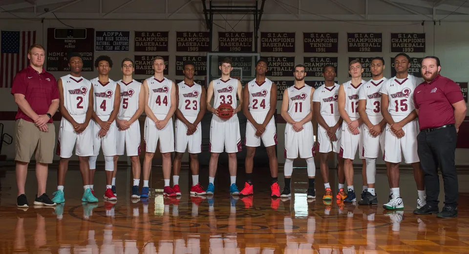 Un gruppo di studenti della West Nottingham Academy posa insieme sul campo da basket con striscioni sullo sfondo.