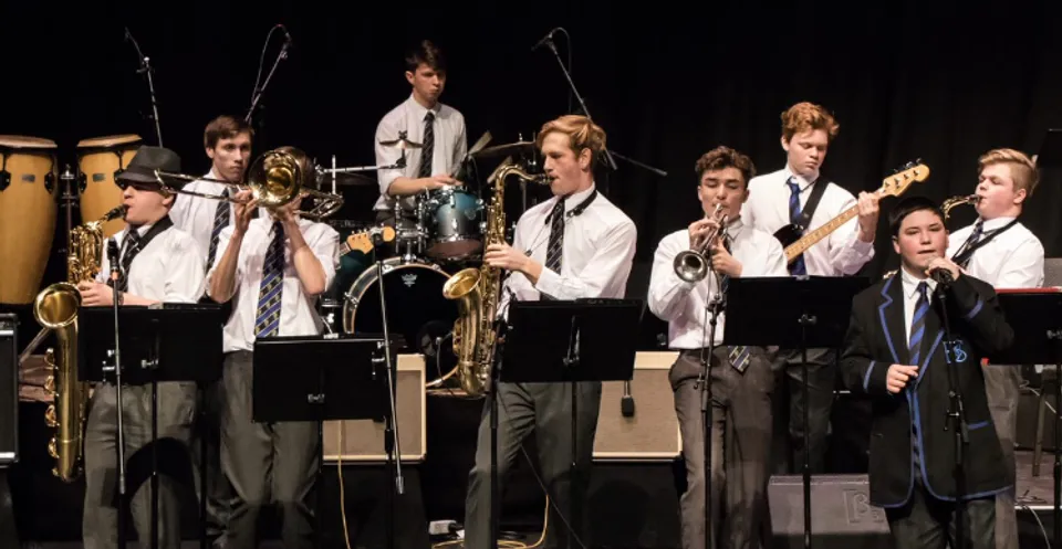 Studenti della Christchurch Boys High School si esibiscono sul palco in abbigliamento formale con tamburi e sassofoni.
