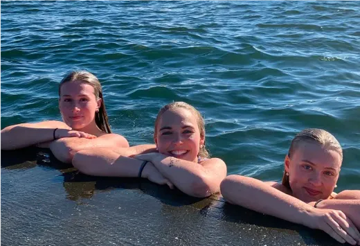 Drei lächelnde Mädchen kühlen sich im Wasser eines Sees in Kanada ab