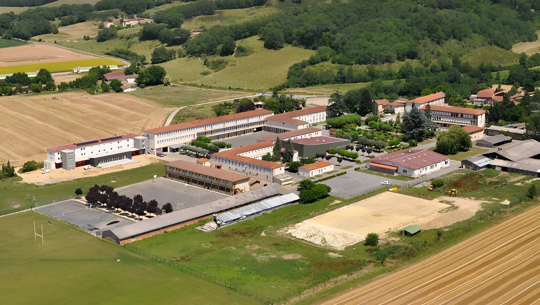 Il Campus La Salle Saint Christophe immerso in un paesaggio verde con campi ed edifici visto dall'alto.