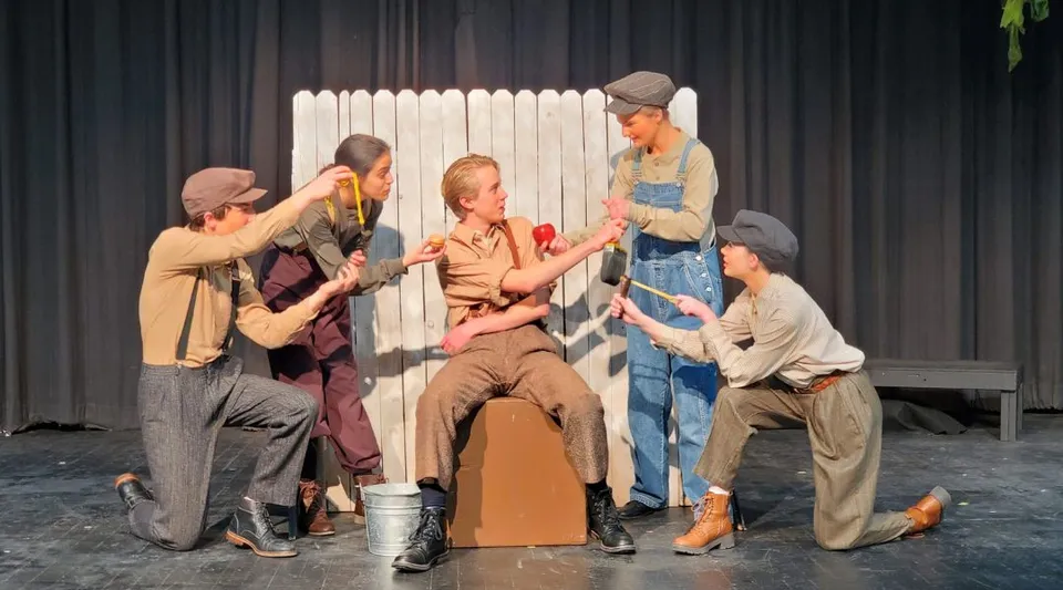 Studenti della Bishop Kelly High School mettono in scena uno spettacolo teatrale su un palco con una staccionata in legno come scenografia.