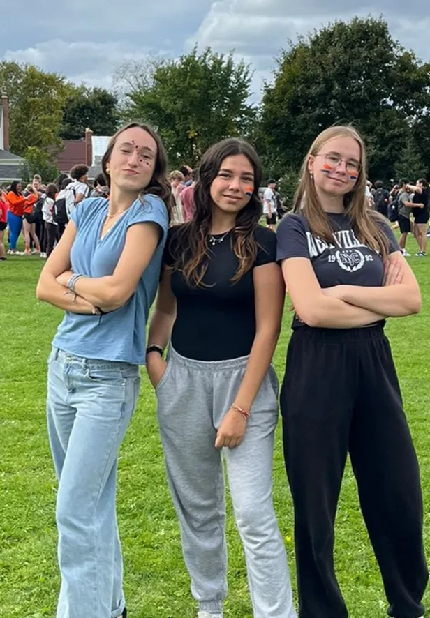 Tres estudiantes con la cara pintada posando en el campo del colegio