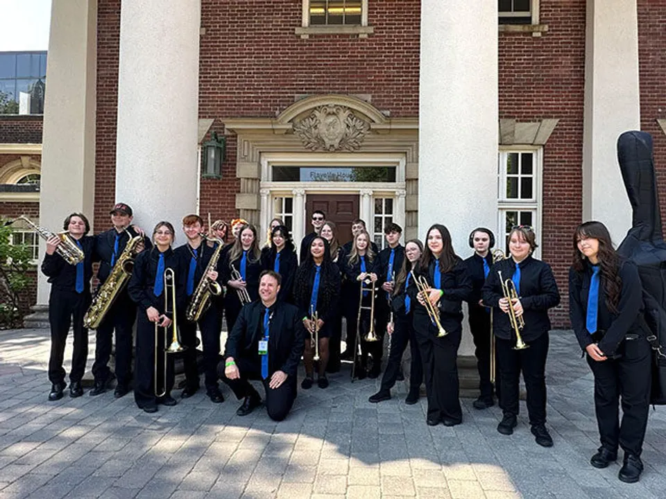 Un gruppo di musicisti si trova davanti all'edificio storico della Brocklehurst Secondary School.
