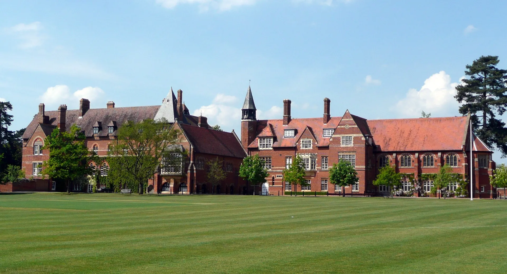 L'edificio storico in mattoni della Abingdon School si erge dietro un curato prato verde sotto un cielo blu.